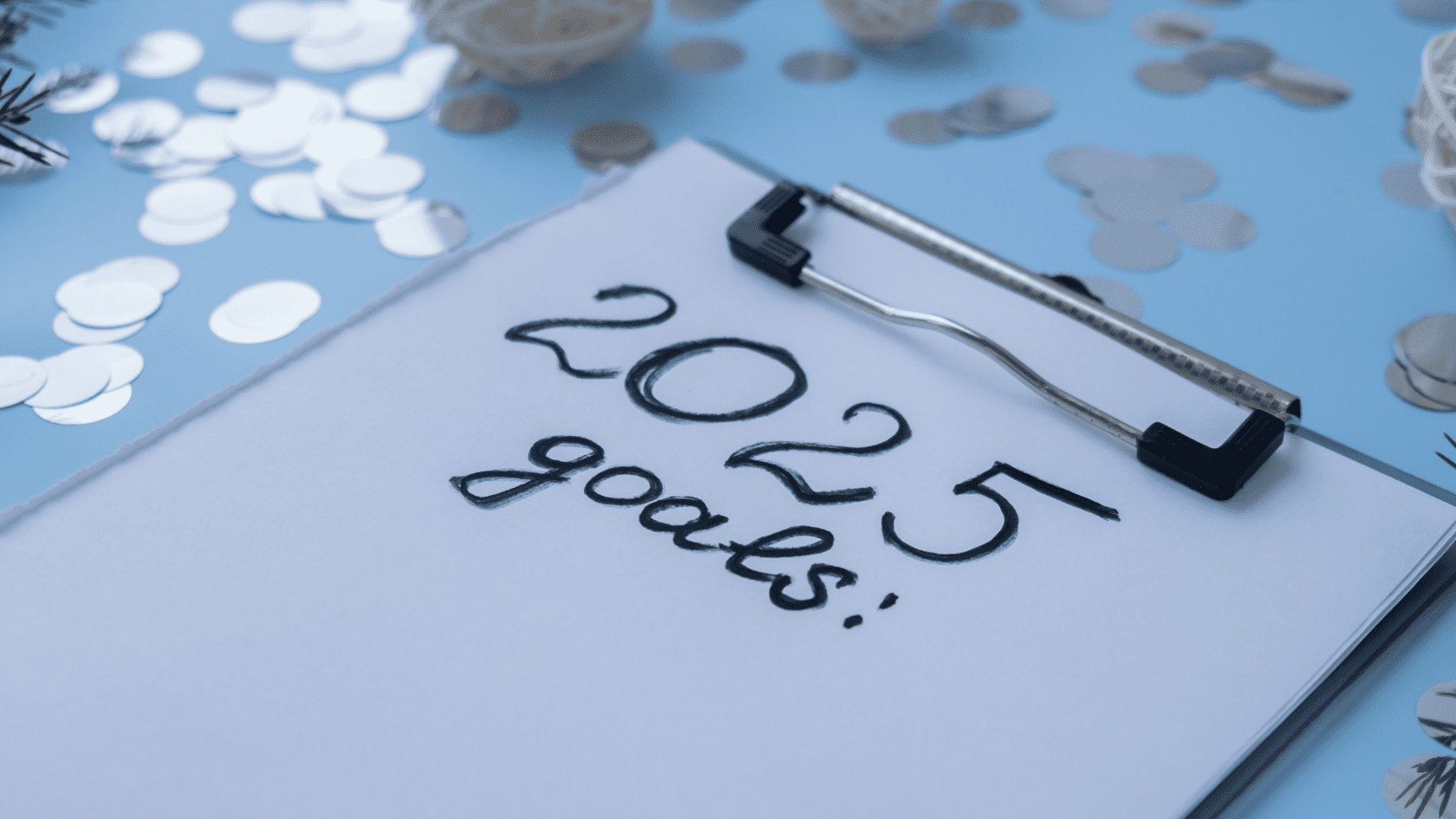 A clipboard with a handwritten text: 2025 goals. This image illustrates a post about oral health New Year's resolutions.